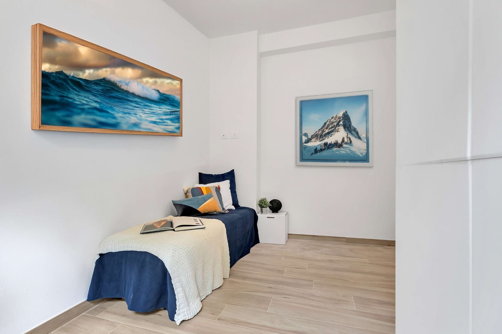 Camera singola inquadrata dall'altro lato, con quadro sopra il letto e pavimento effetto legno