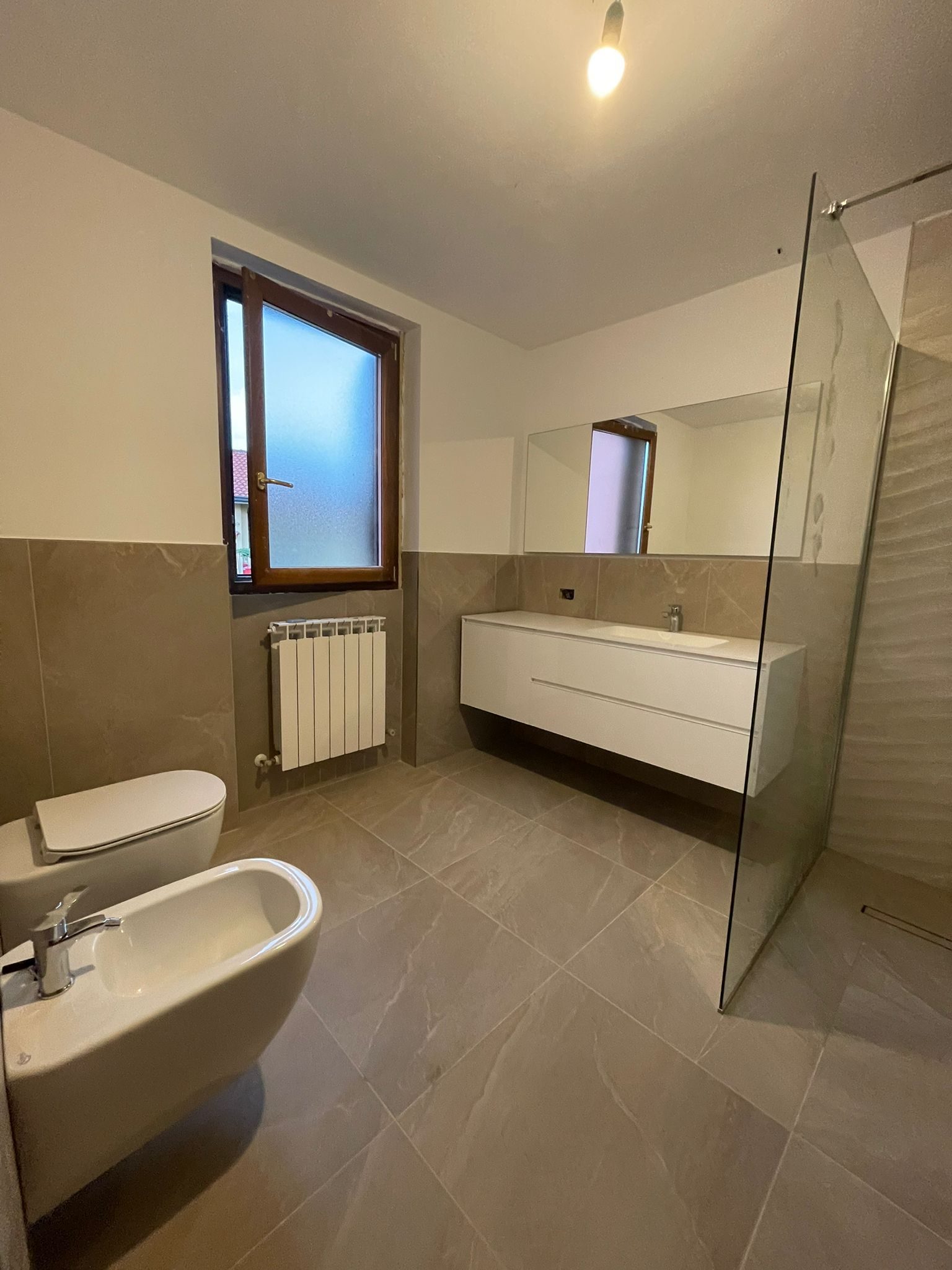 Vista d'insieme del bagno finito con vasca e specchio a filo