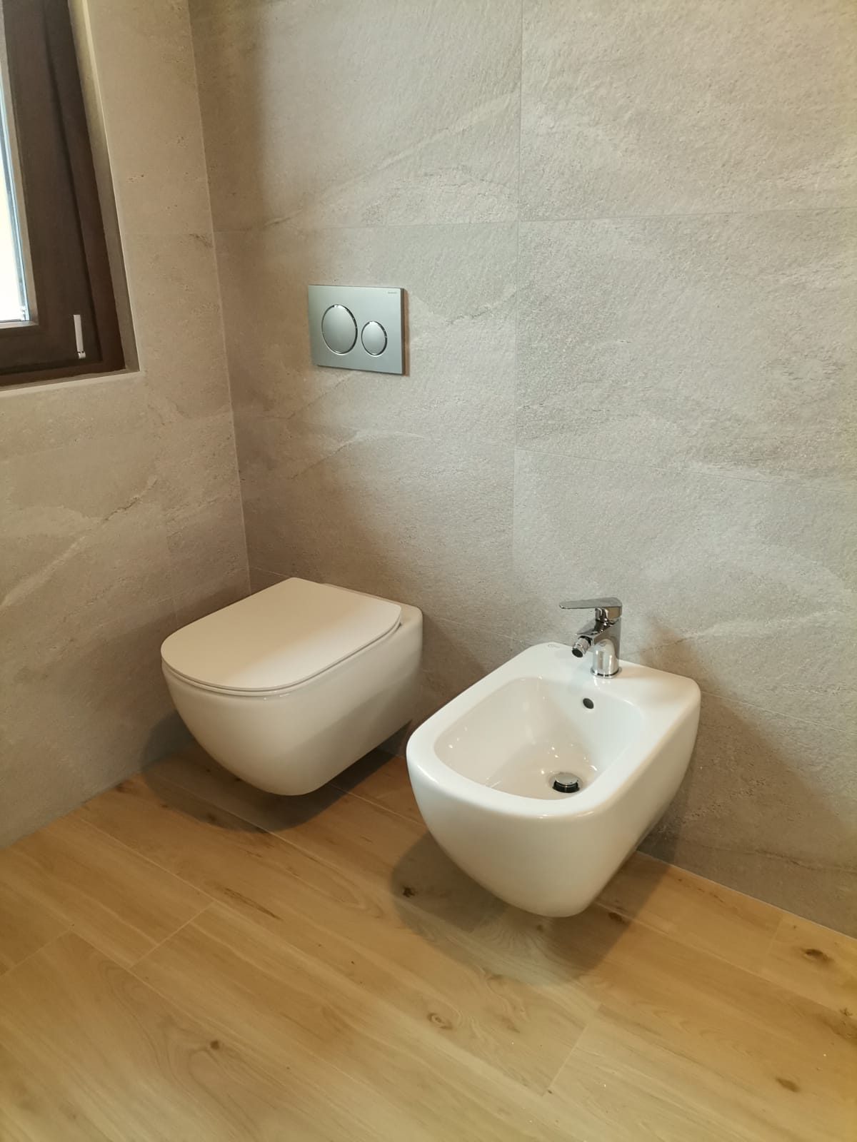 Sanitari sospesi e pavimento effetto legno in un bagno appena consegnato