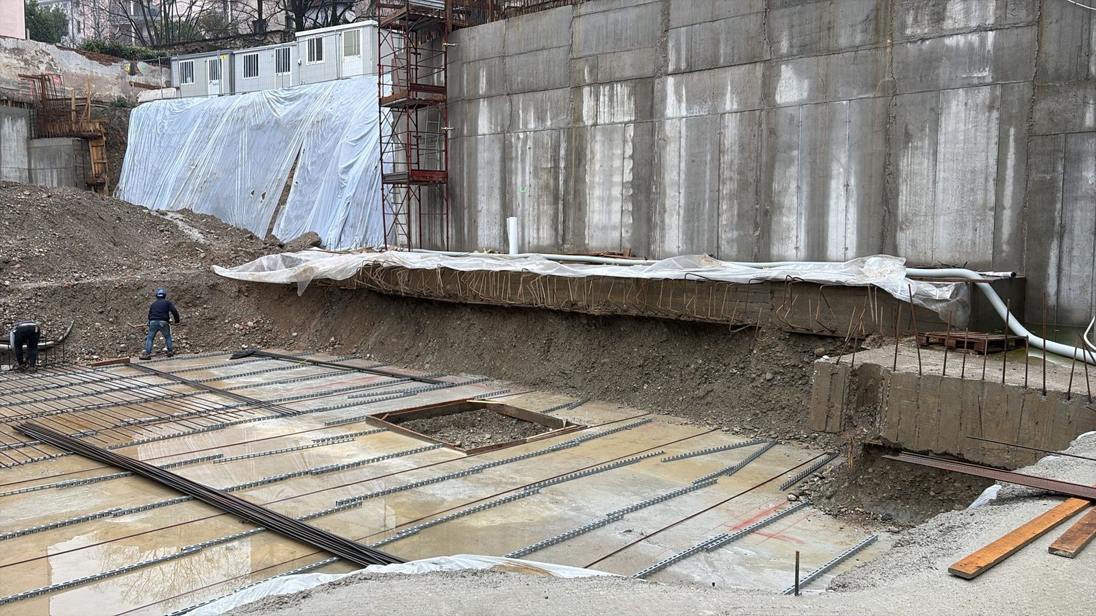 Scavo di cantiere con muro in cemento armato e armatura della platea di fondazione