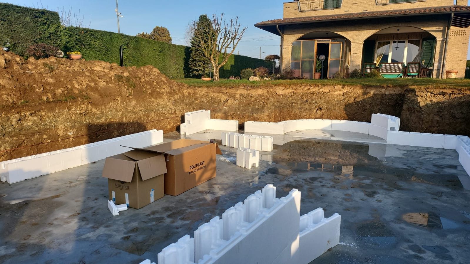Scavo per piscina con platea gettata e casseri in polistirolo bianco posati lungo il perimetro