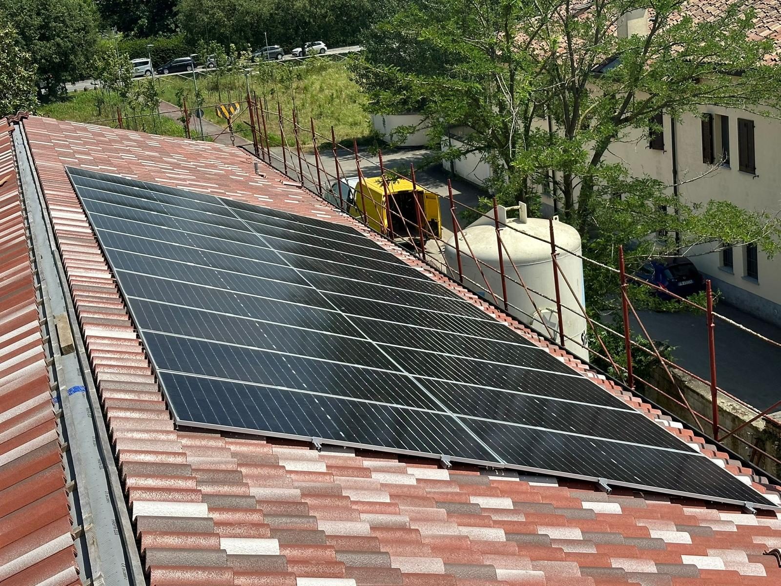 Moduli fotovoltaici posati su falda in tegole, con ponteggio perimetrale e silo da cantiere