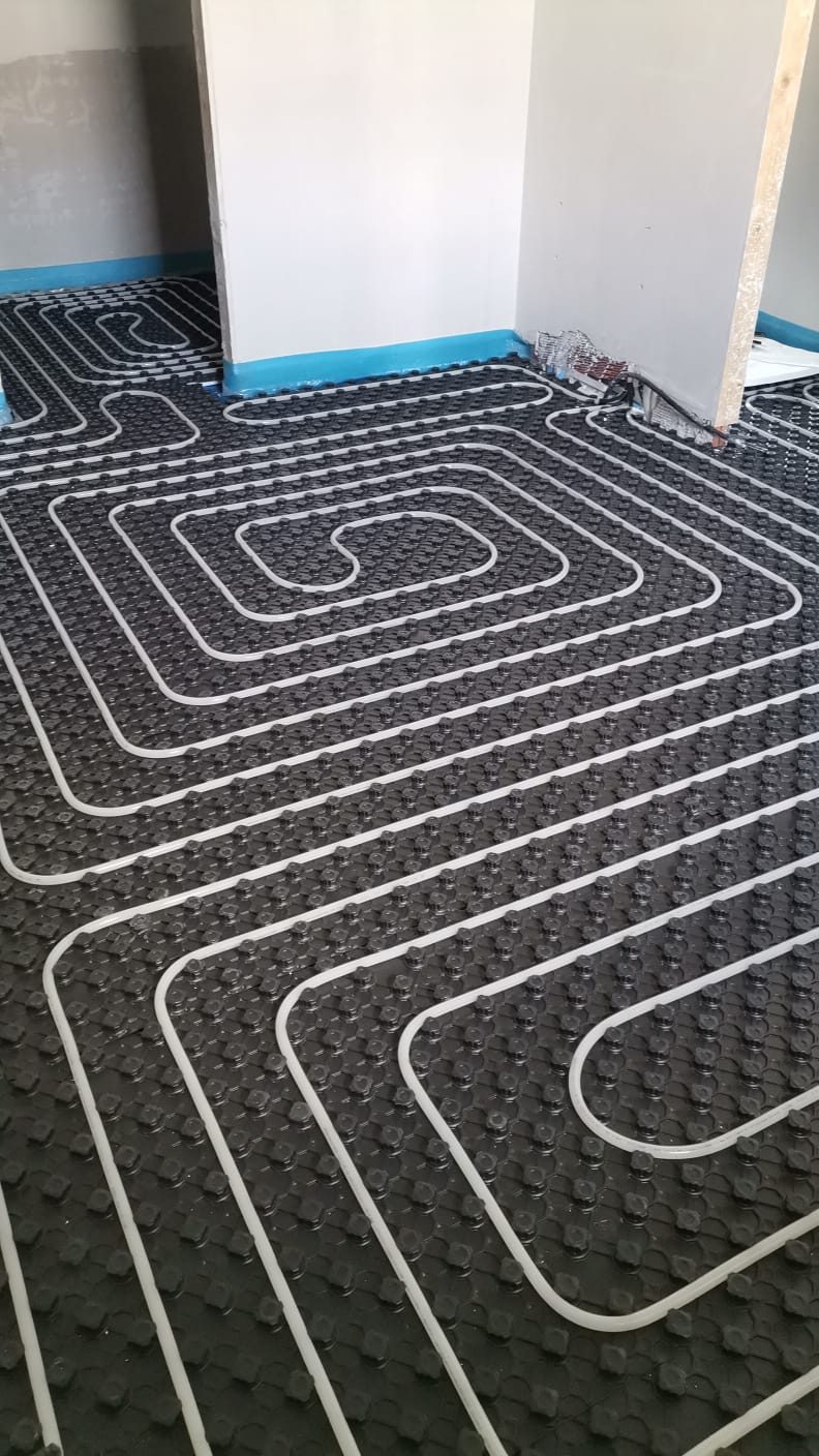 Pannello bugnato nero con tubo del riscaldamento a pavimento posato a spirale, fascia perimetrale blu