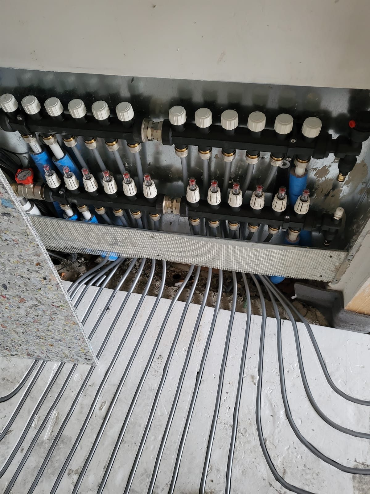 Collettore di riscaldamento a pavimento con flussometri e tubazioni dei circuiti posate nei pannelli
